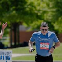A participant running while spectators cheer him on.